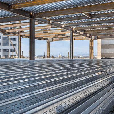 پایه‌های فلزی و اسکلت ساختمان در حال ساخت، نمایی از پروژه مهندسین مشاور عمران سازه در حال توسعه و اجرای سازه‌های بتنی و فلزی در محیط شهری.